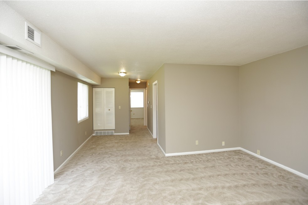 the spacious living room and dining room of an empty house