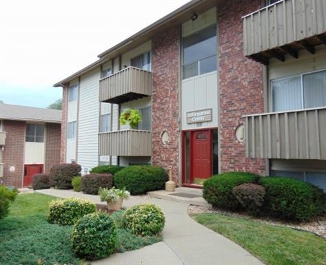 an apartment building with a red door and a sidewalk