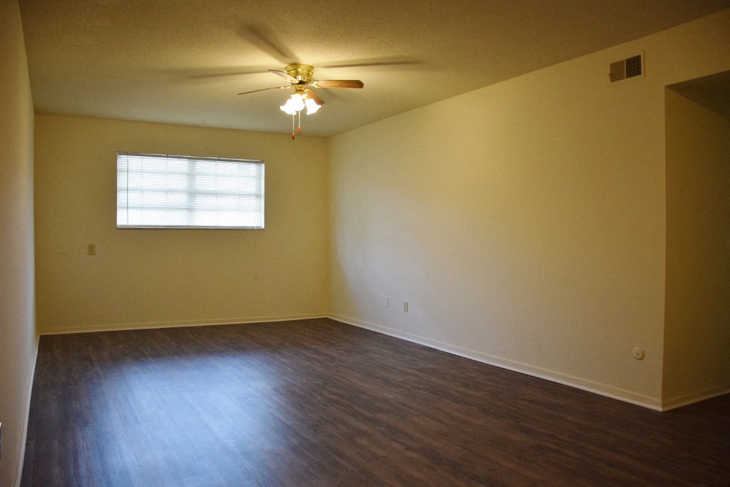 an empty living room with a ceiling fan and a window