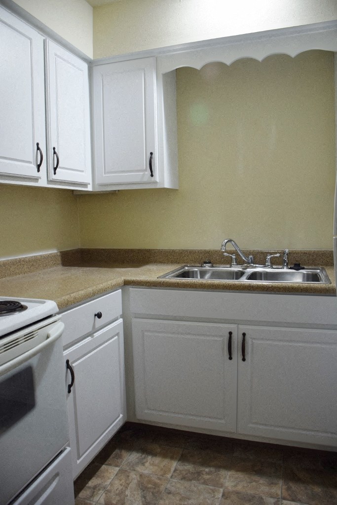 a kitchen with white cabinets and a sink and a stove