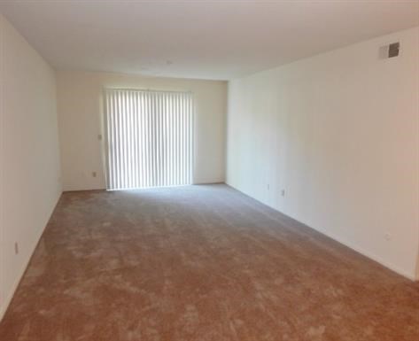 an empty living room with a white wall and a window