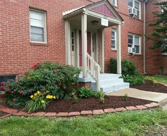 a front porch with a flower garden in front of a brick house