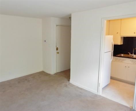 an empty room with a refrigerator and a kitchen