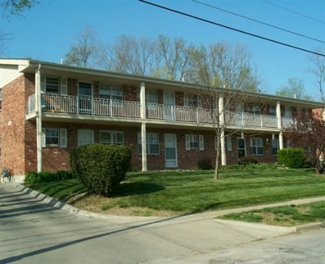 a brick apartment building with a porch and a lawn
