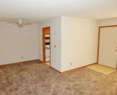 an empty living room with a ceiling fan and a door