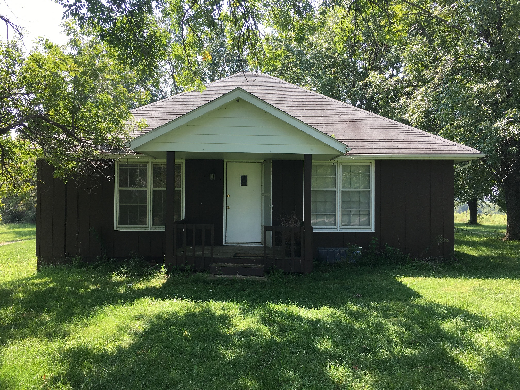 the front of a small brown house with a porch