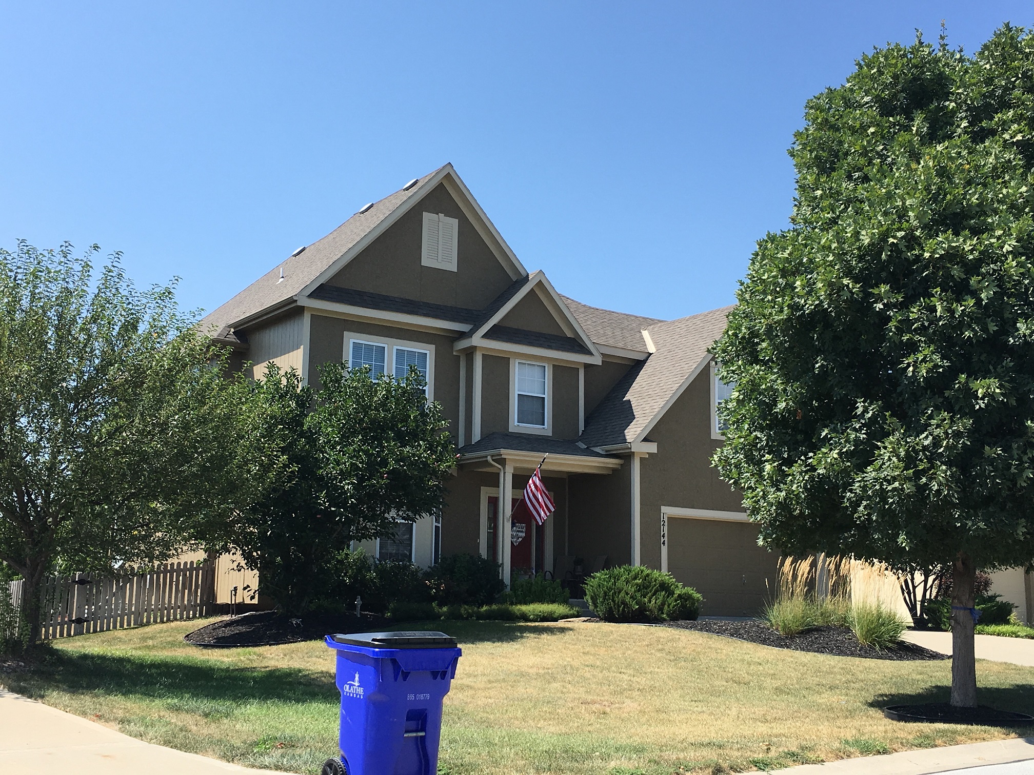 a house with a blue trash can in front of it