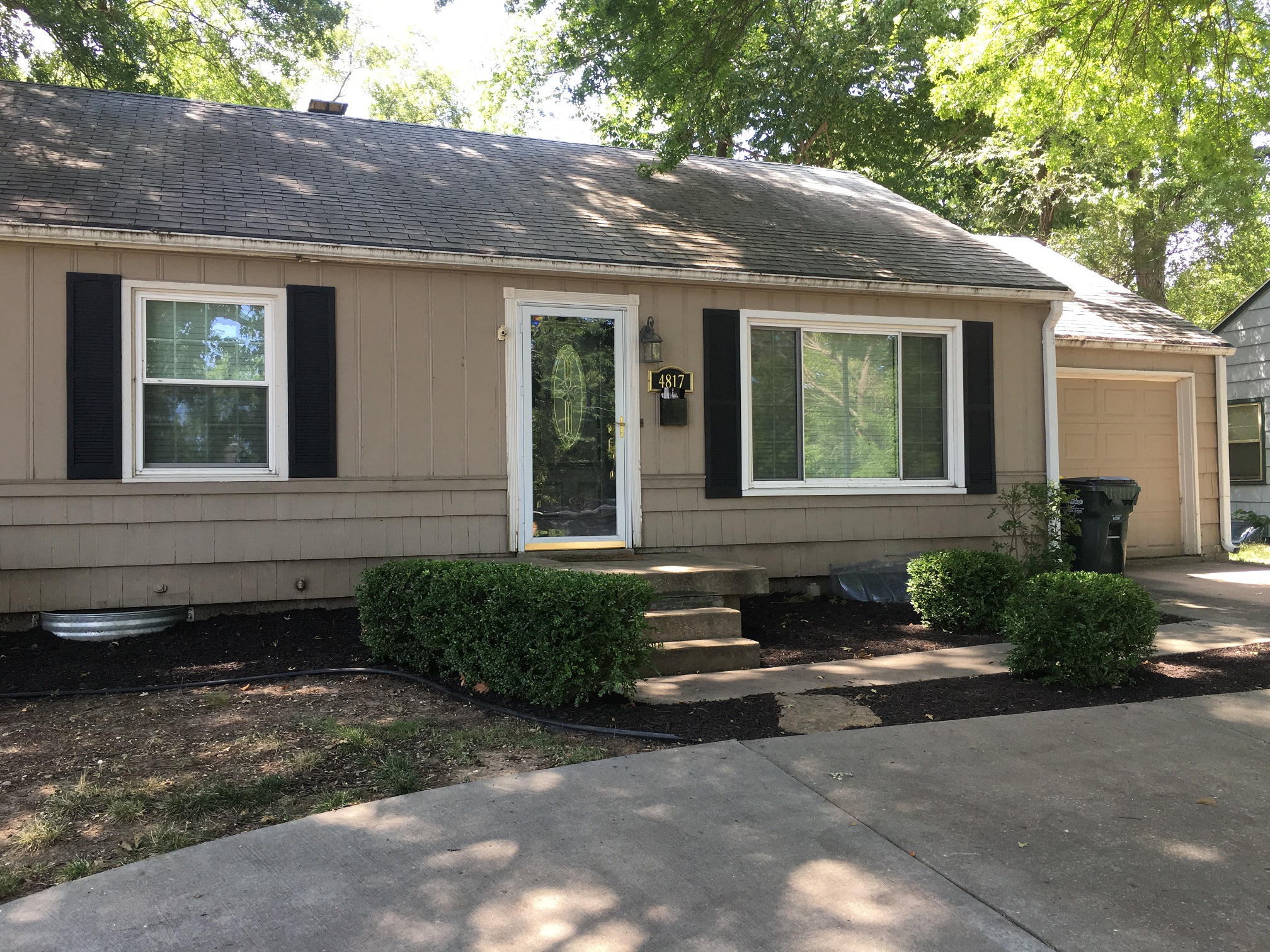 the front of a house with black shutters and a sidewalk