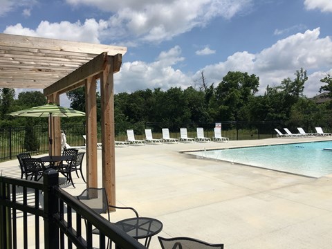 A pool area with a table and chairs and a green umbrella.