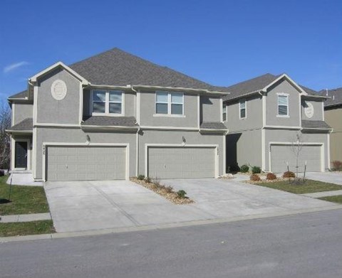 a gray house with two garage doors and a driveway