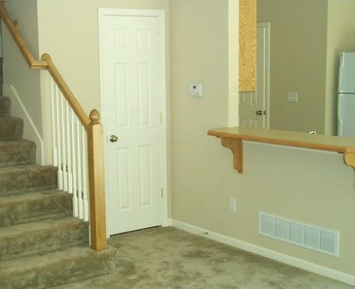 a living room with stairs and a white door