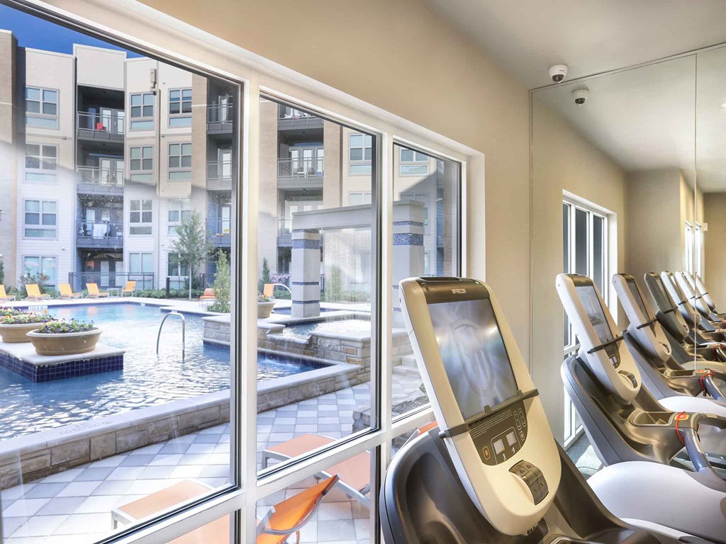 a gym with cardio equipment and a pool in a building