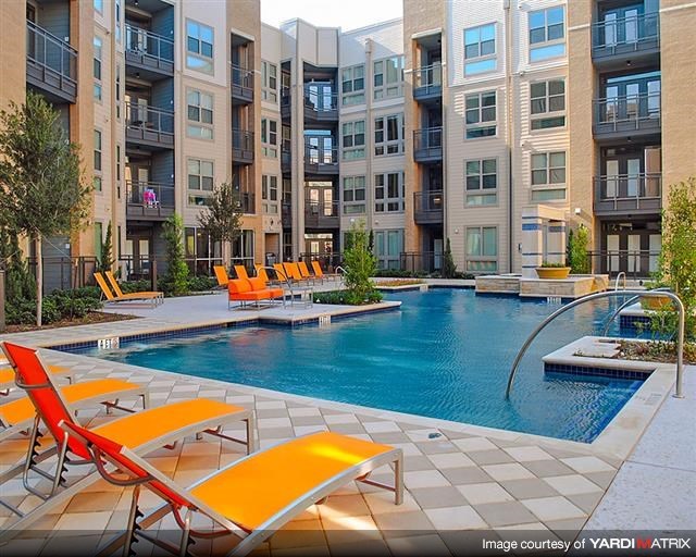 a swimming pool with orange chairs in front of an apartment building
