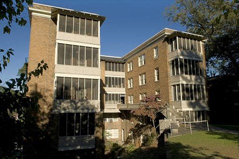A large building with a lot of windows and a tree in front.