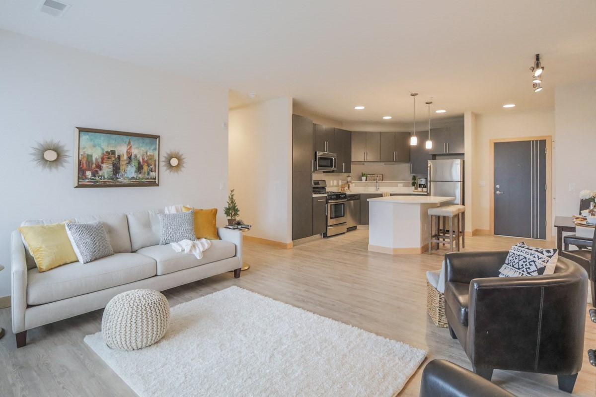 a living room with a couch and a chair in front of a kitchen