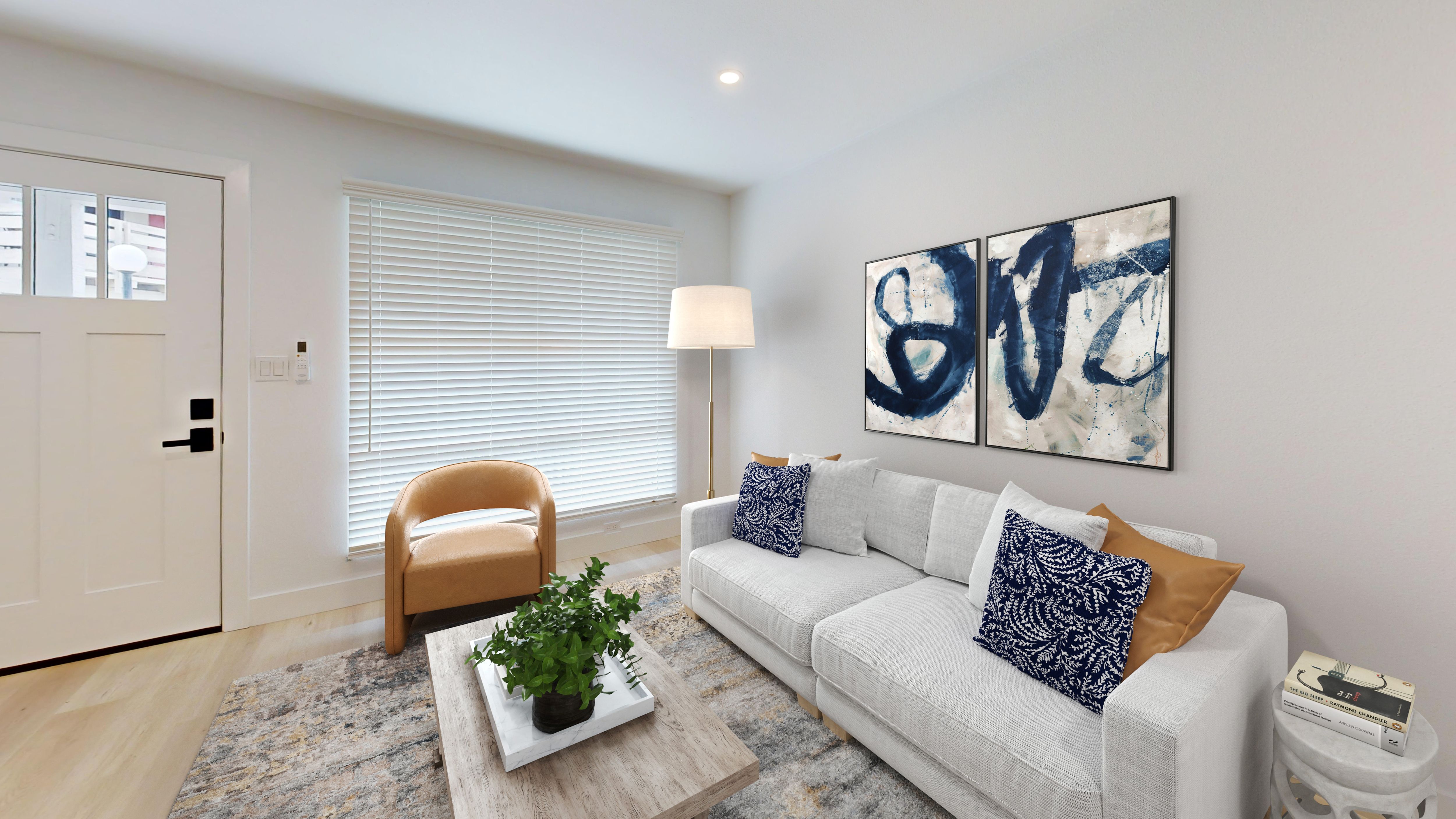 A living room with a white couch, a plant on a coffee table, and a painting on the wall.