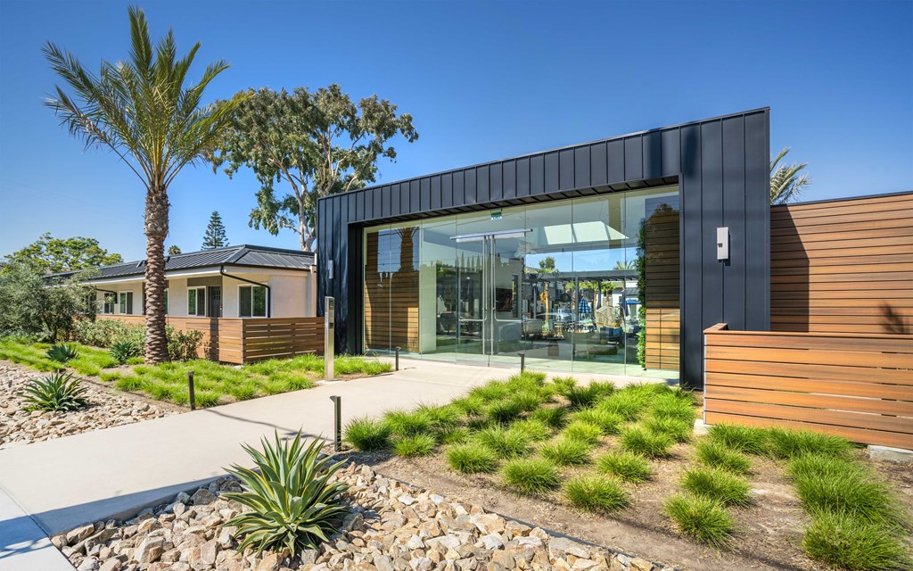 a modern house with glass windows and a sidewalk