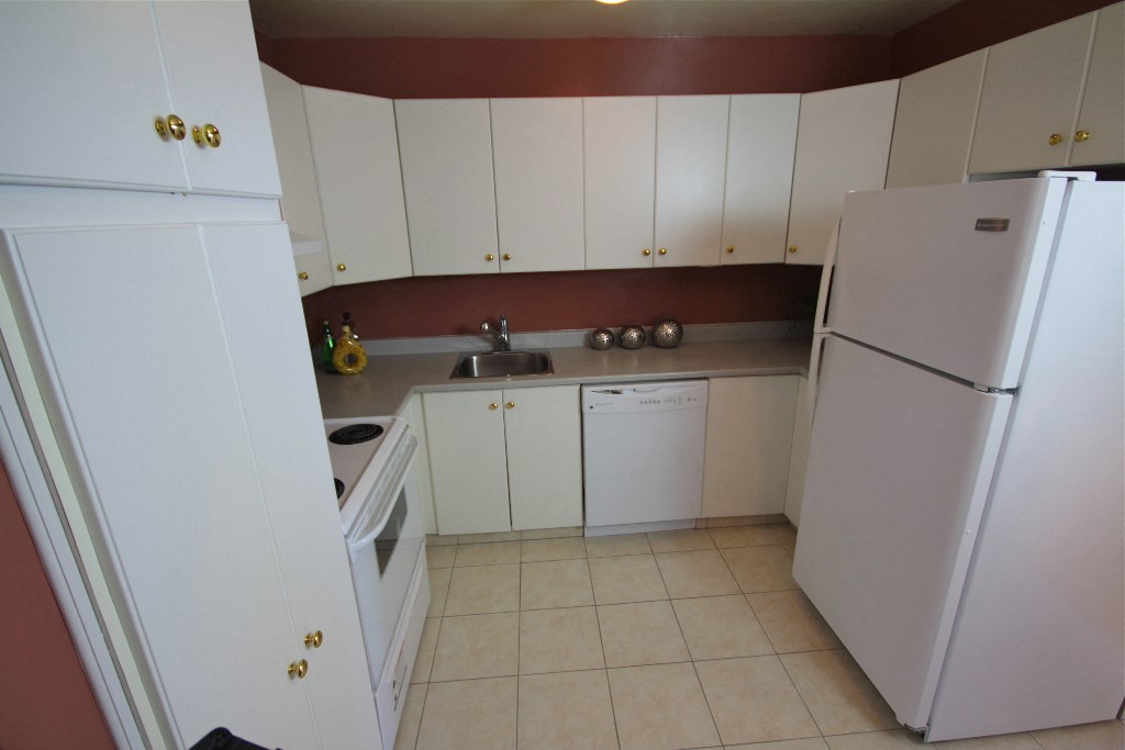 a kitchen with white cabinets and a refrigerator and a sink