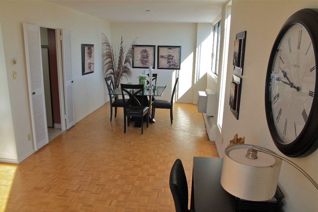 a dining room and living room with a large clock and a table and chairs