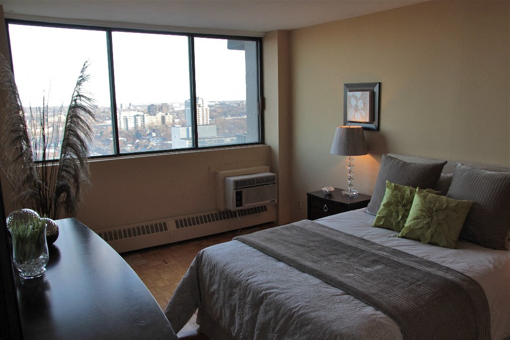 a bedroom with a large window and a bed and a desk