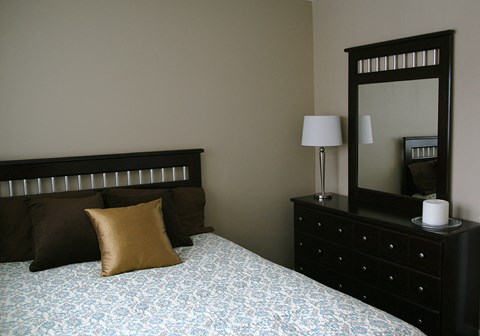 a bedroom with a bed and a dresser with a mirror