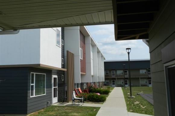 a sidewalk in front of a row of apartments