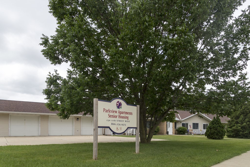 a building with a sign in the grass in front of a tree