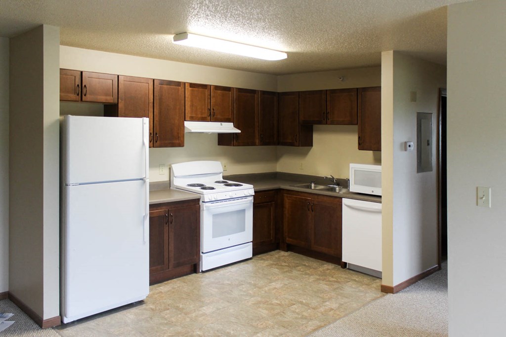 an empty kitchen with white appliances and wooden cabinets