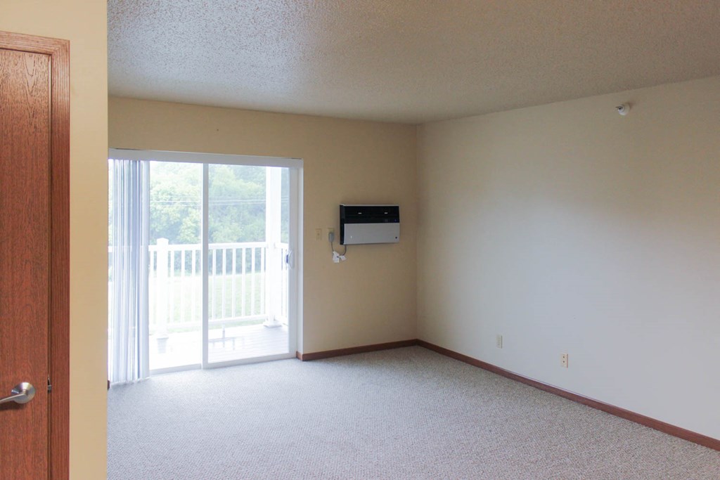 an empty living room with a sliding glass door to a balcony