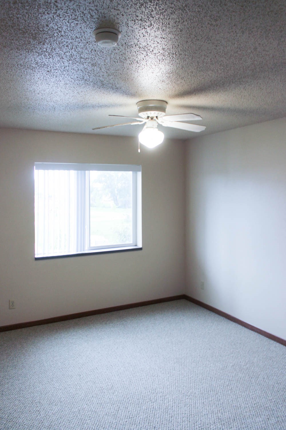 an empty room with a ceiling fan and a window