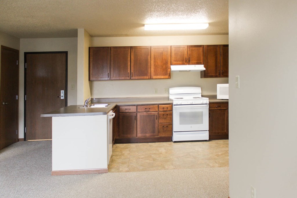 an empty kitchen with white appliances and wooden cabinets