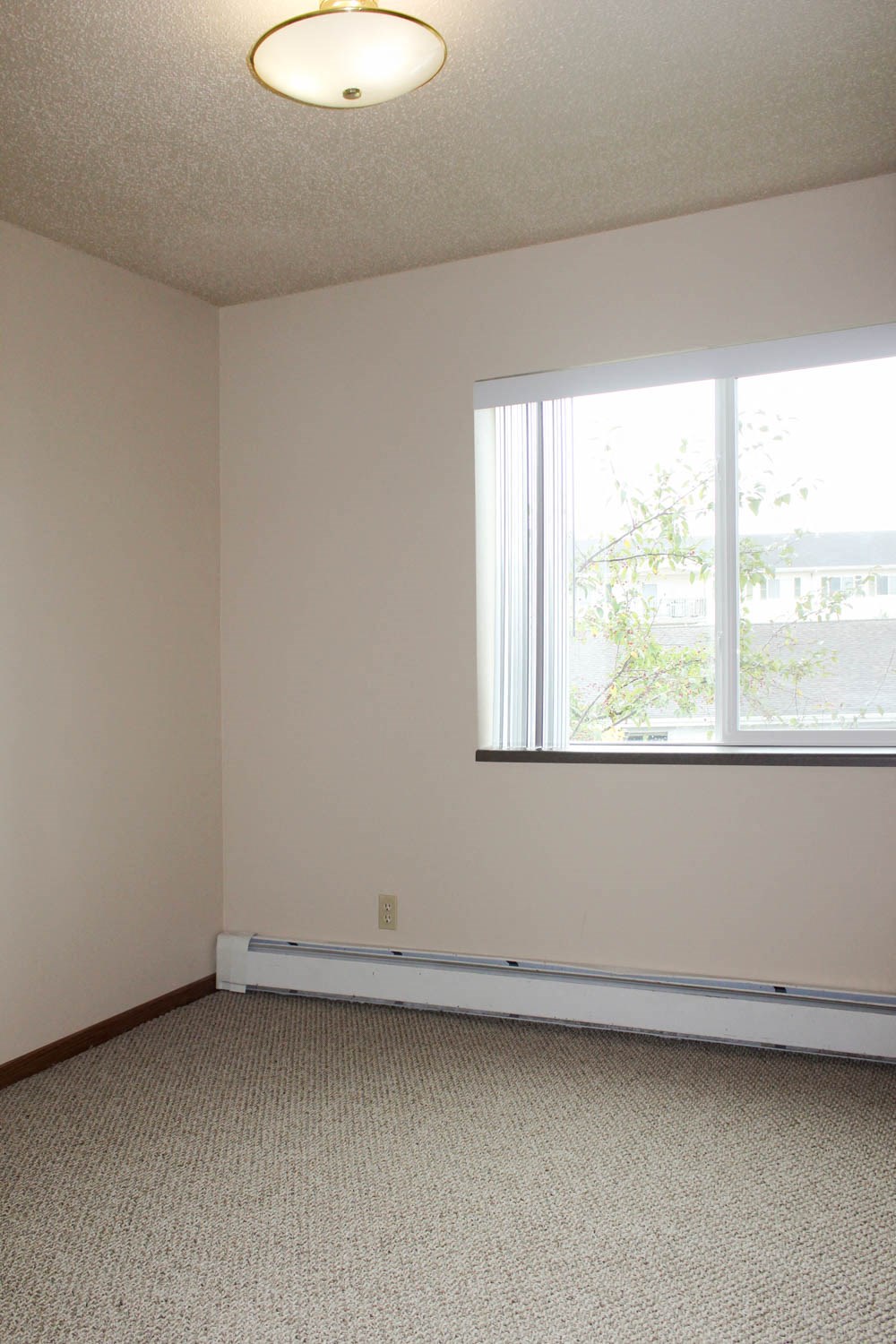 an empty room with a large window and a carpet