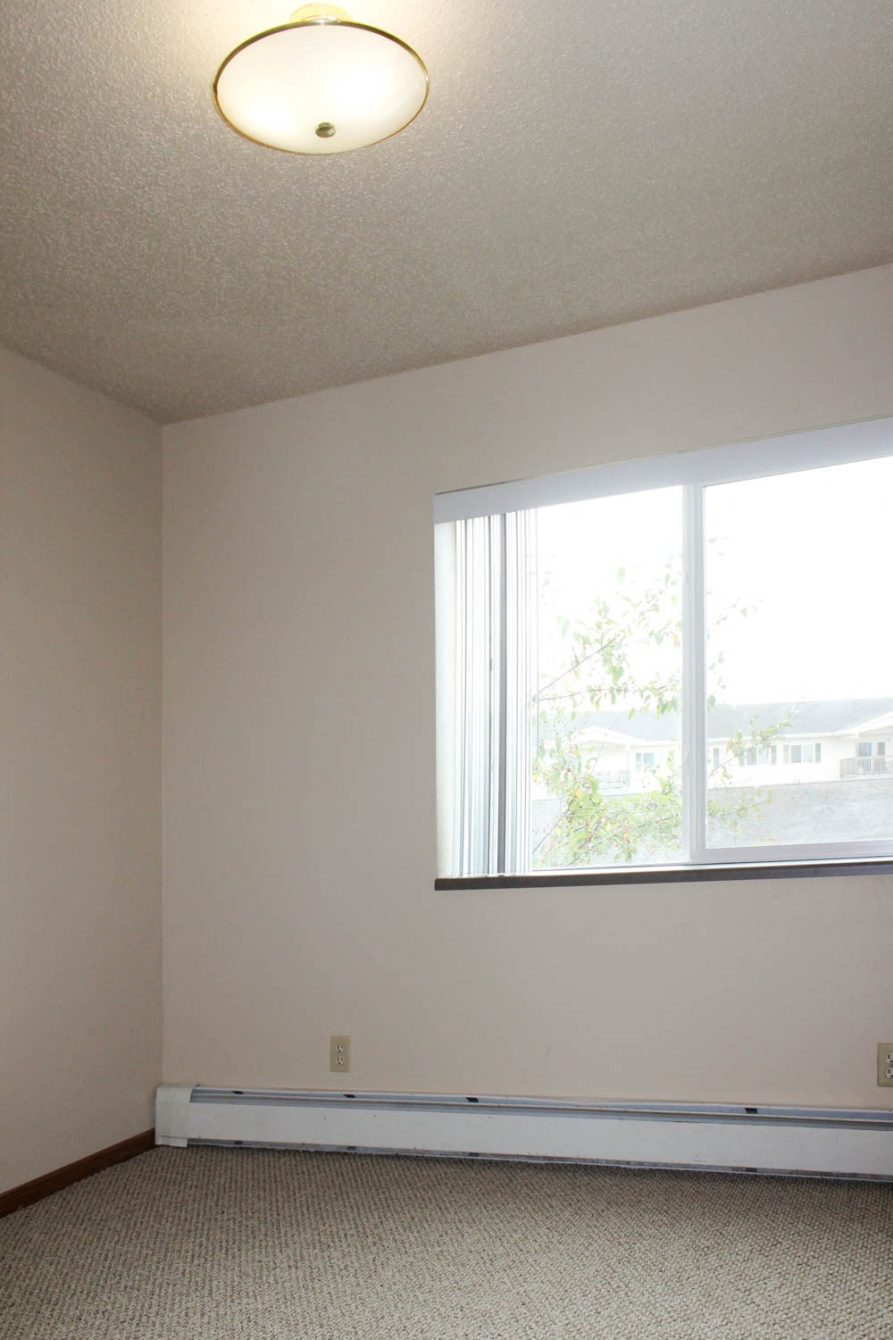 an empty room with a large window and white walls