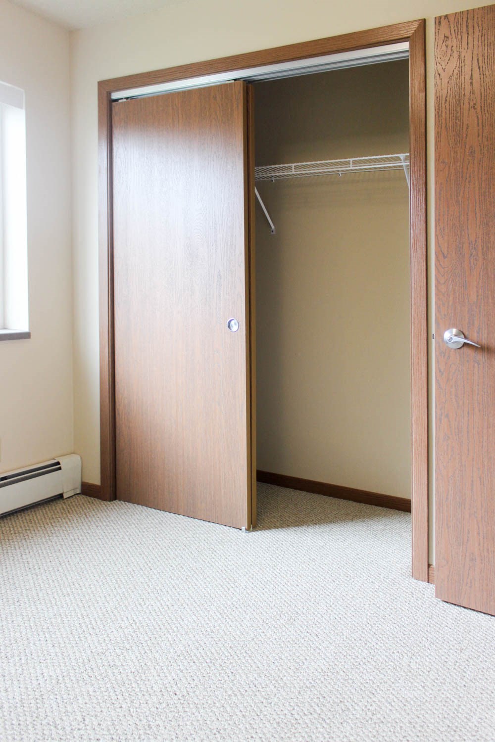 a bedroom with a closet and a carpeted floor