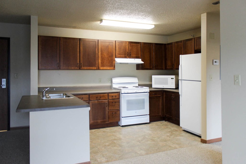 an empty kitchen with white appliances and wooden cabinets