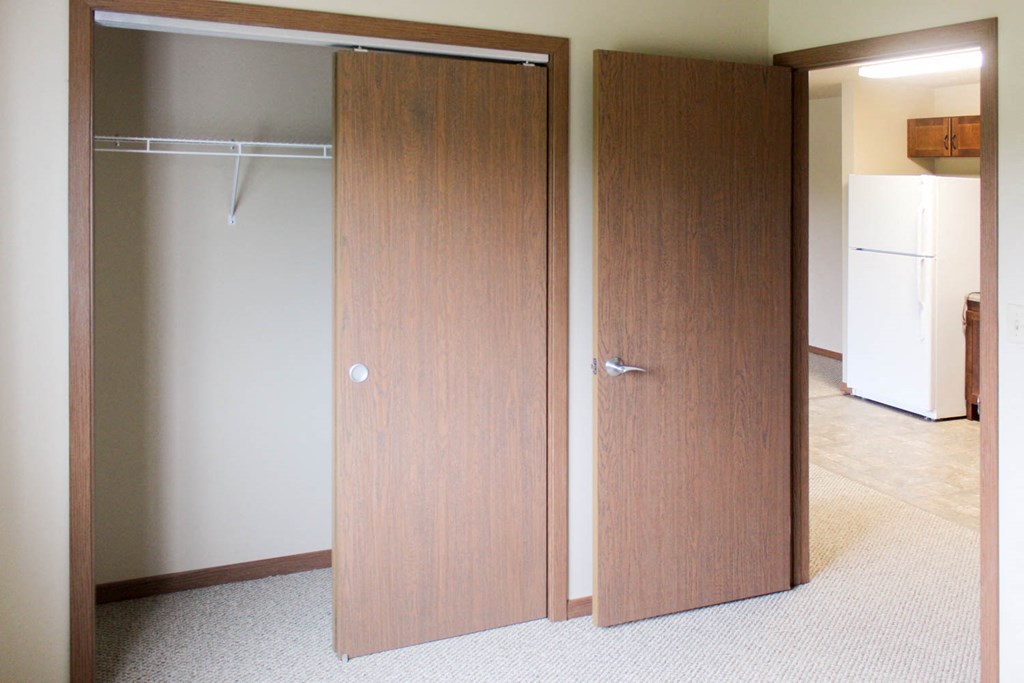 an empty room with a closet and a refrigerator