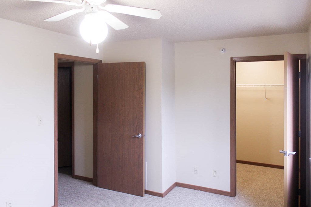 an empty bedroom with a closet and a ceiling fan