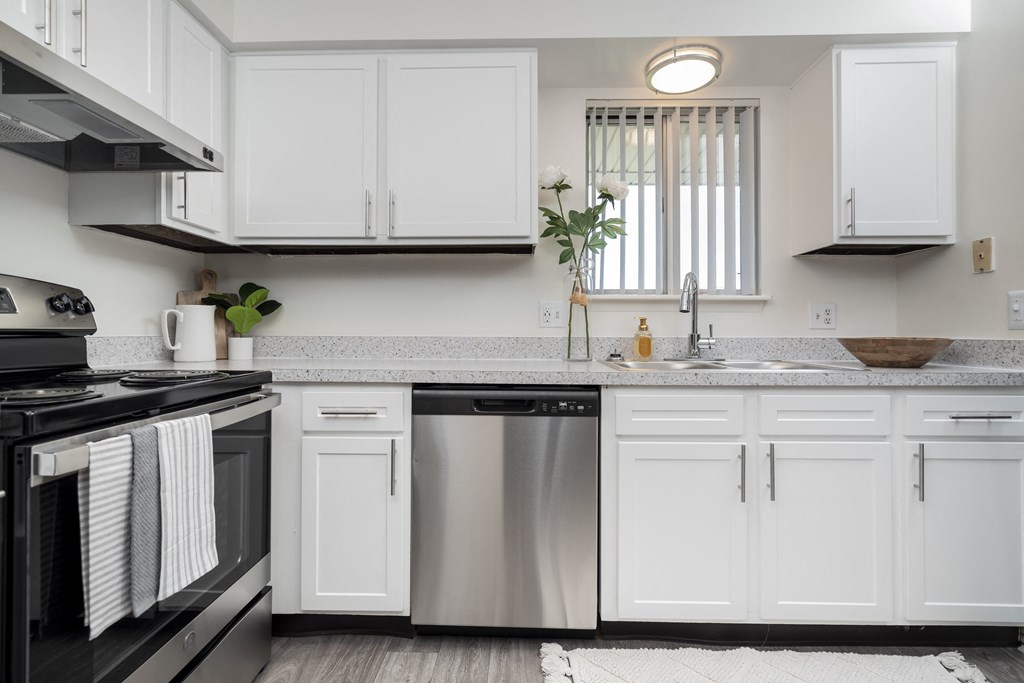 a white kitchen with stainless steel appliances and white cabinets