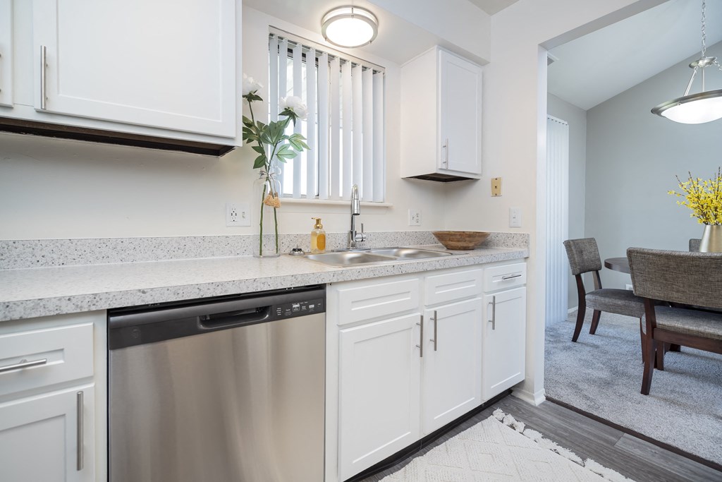 a kitchen with white cabinets and a stainless steel dishwasher