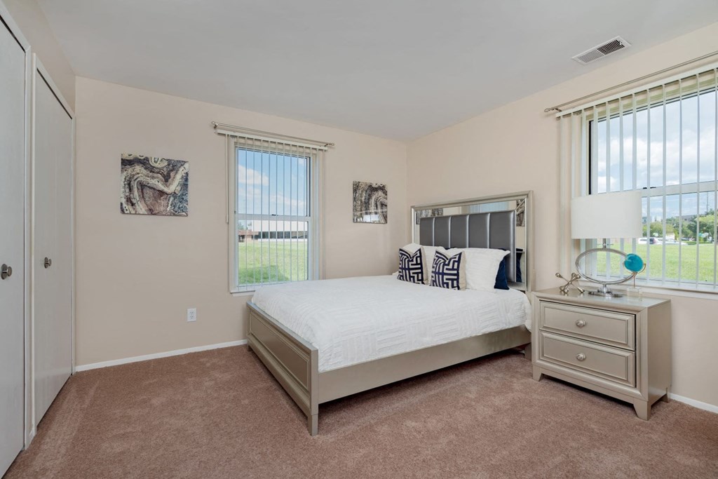 a bedroom with a bed and two windows