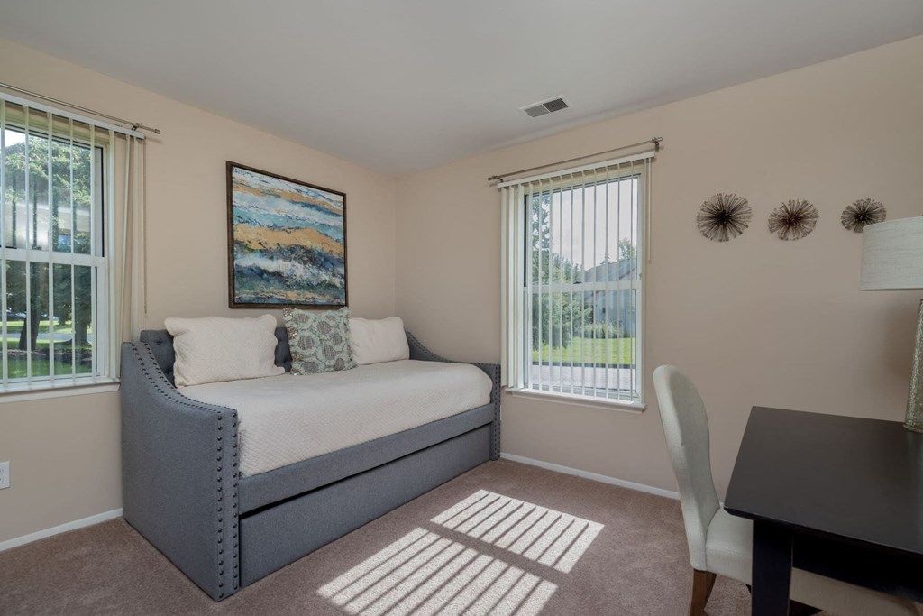 a bedroom with a bed and a desk and a window