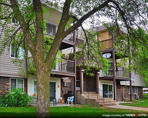 an apartment building with a tree in the yard