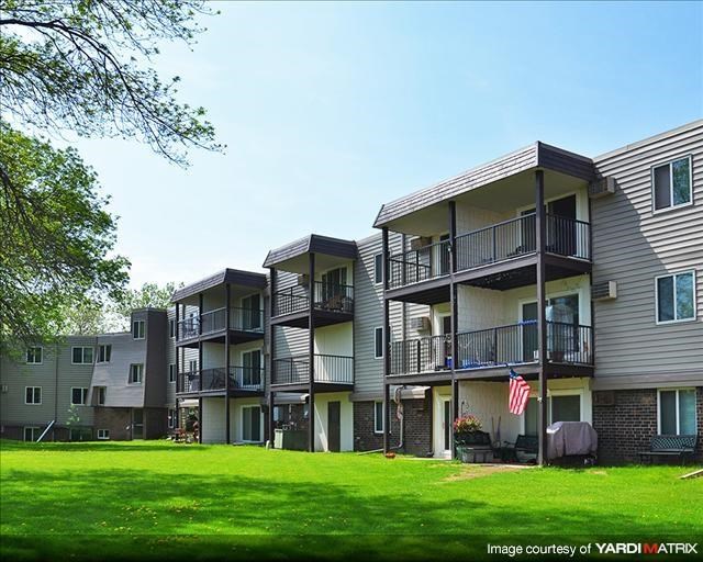 a row of apartment buildings with a green lawn