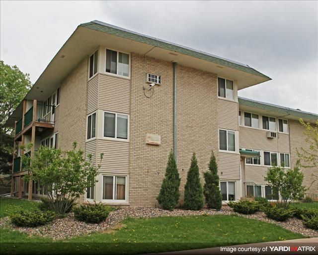 a large brick apartment building with a green yard