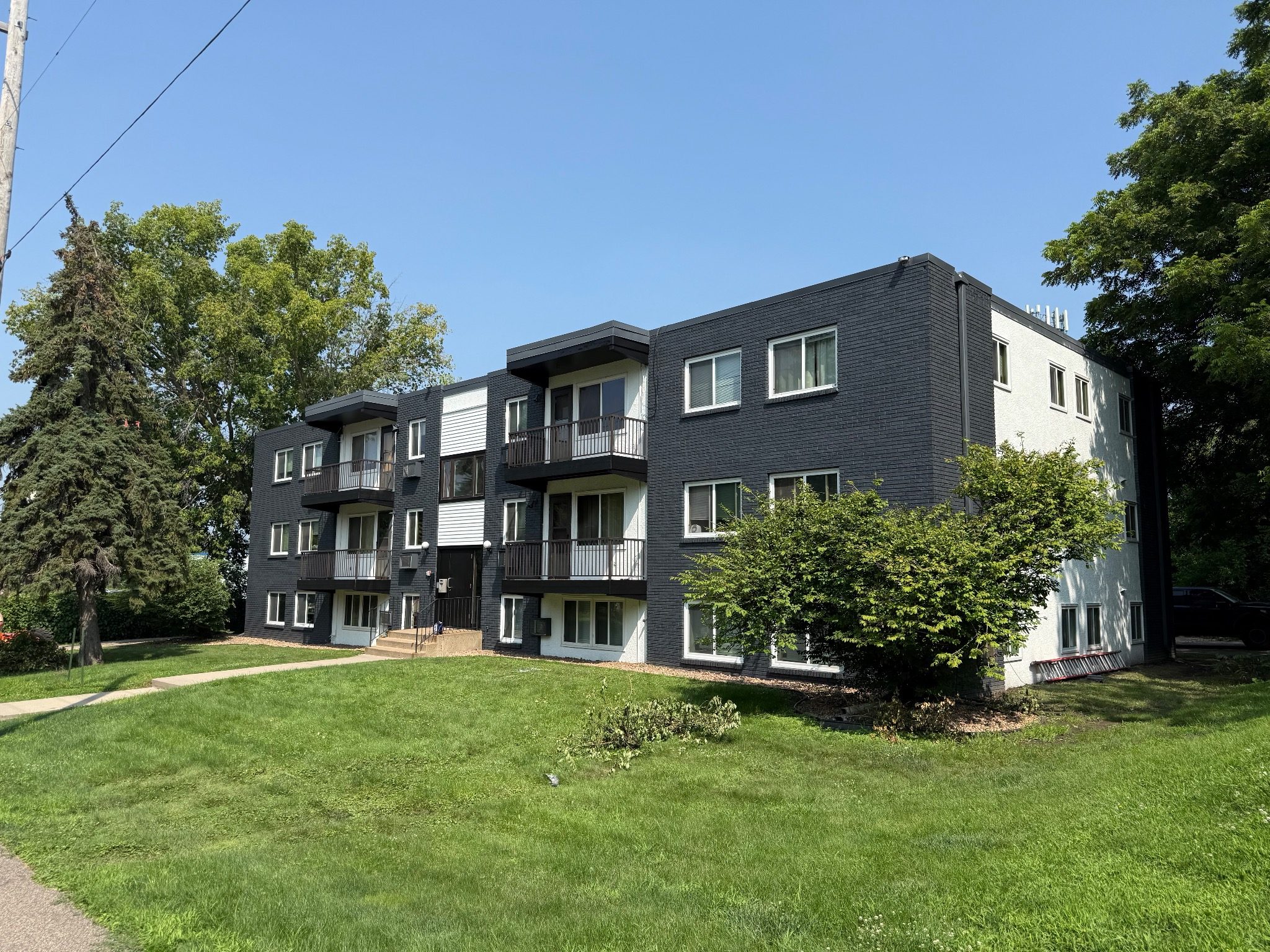 A black and white apartment building with a green lawn in front.