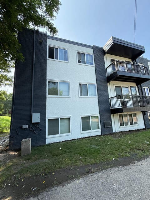 A modern two-story apartment building with a balcony on the upper floor.