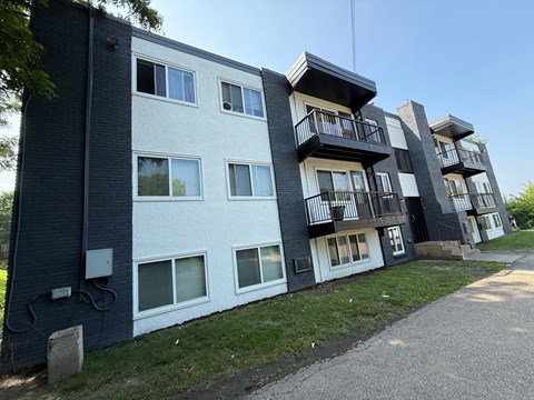 A modern apartment building with balconies and a mix of white and dark exterior walls.