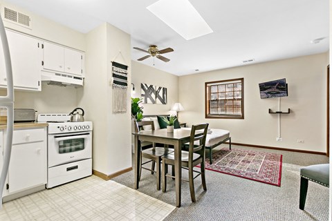a kitchen with a dining table and a stove and a ceiling fan