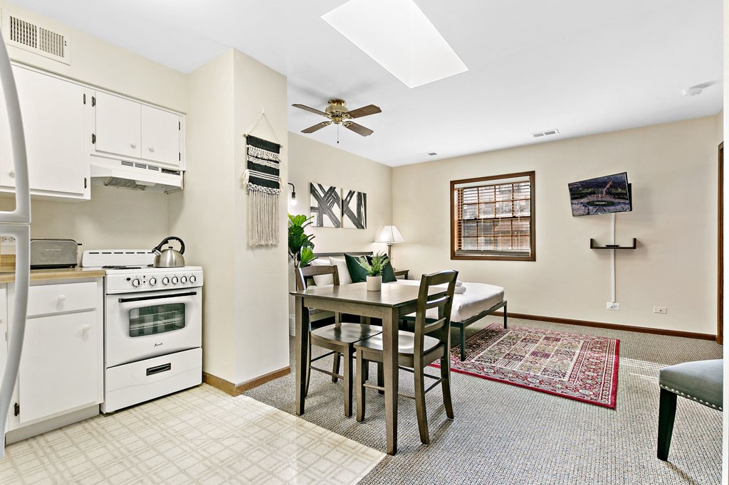 a kitchen with a dining table and a stove and a ceiling fan