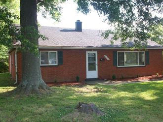 a view of the front of a brick house with a tree